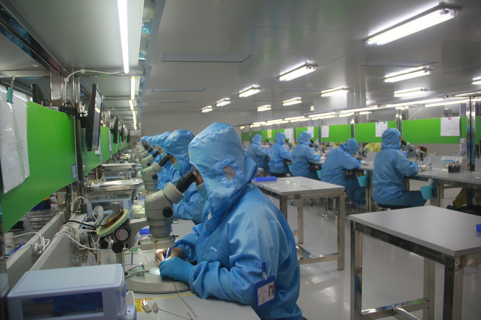 Technicians in protective cleanroom suits working at inspection benches in a GMP facility